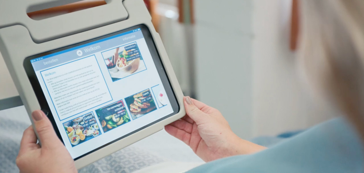 مريضة تنظر إلى شاشة iPad أثناء جلوسها على سريرها في المستشفى.